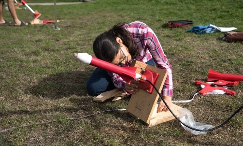 A student sets a homemade rocket up for launch.