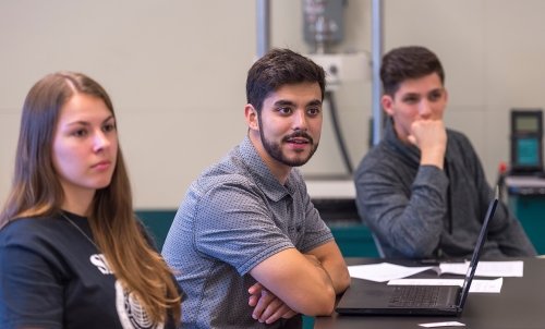 Close up of three students listening in class.