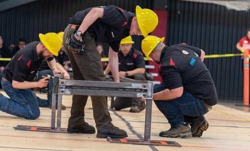 Student in yellow hard hats work on a metal structure