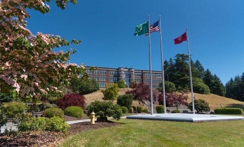 Photo of Old Main, with the flags in the foreground.