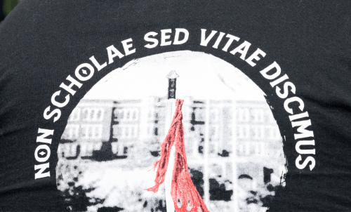 Closeup of tshirt graphic showing a red flag in front of a black and white Old Main, with &quot;non scholae sed vitae discimus&quot; around edges