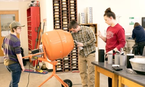 Three engineering students working in class.
