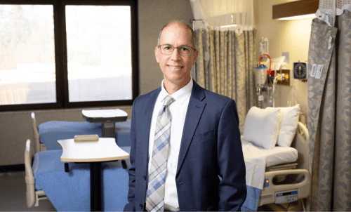 Will Callicoat poses in front of hospital room, with window and bed