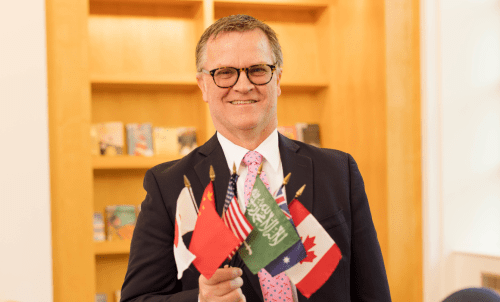 Photo of Roger Douglas holding multiple flags