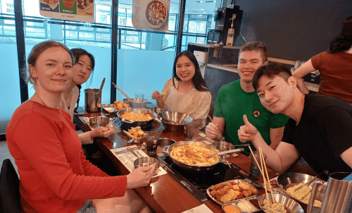 Students sitting around a table filled with food at a restaurant
