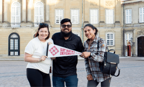 Students hold a Saint Martin's pennant in a European plaza
