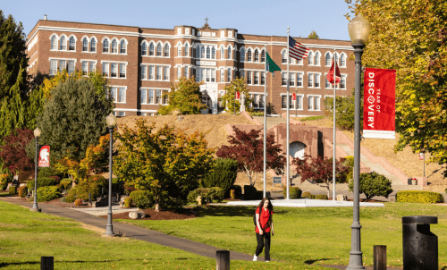 A student walks across a lawn with Old Main in the background