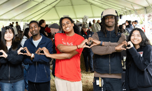 Students stand in row making hearts with hands