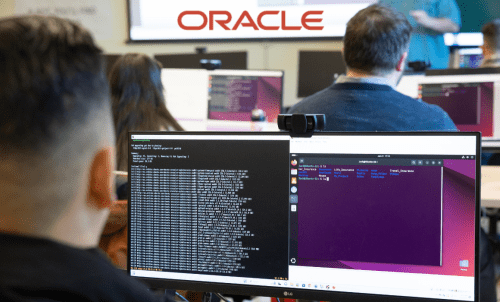 Students work at computers, with the Oracle logo overlaid