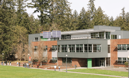 A building in the woods with people walking in front of it