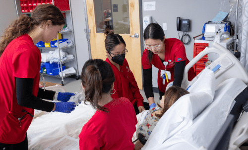 Nursing students in scrubs work in a nursing classroom lab