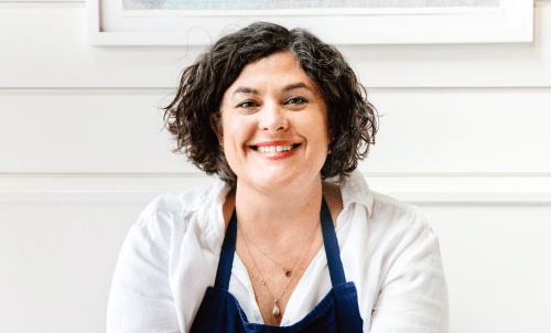 Chef Renee Erickson sits in an apron in front of paneling