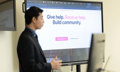 A student gives a presentation in front of a screen showing his project