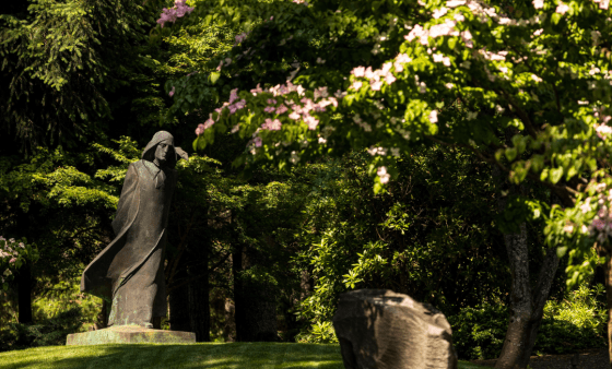 Statue of St. Benedict in a lush spring outdoor setting
