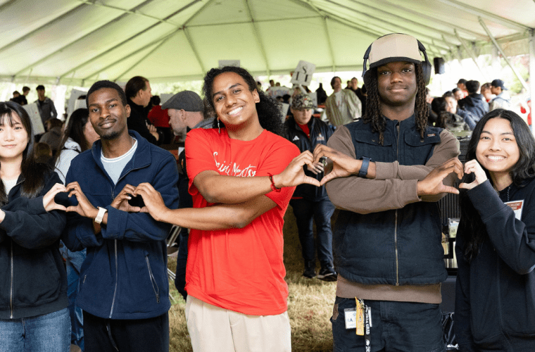 Students stand in row making hearts with hands