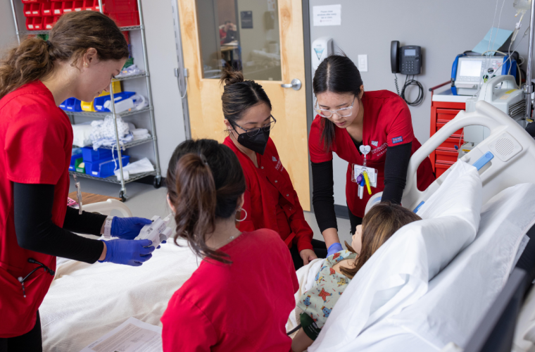 Nursing students in scrubs work in a nursing classroom lab