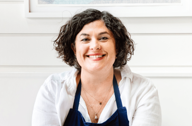 Chef Renee Erickson sits in an apron in front of paneling