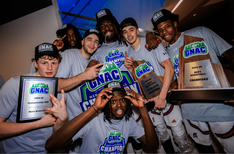 The basketball team wears GNAC tshirts and hold their championship plaques
