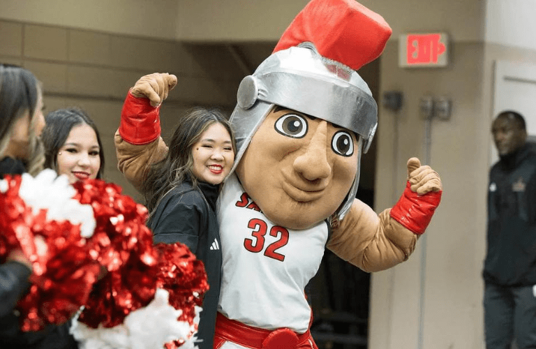Marty poses with student next to cheerleaders