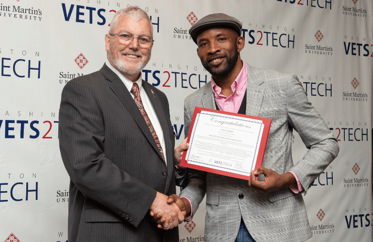 Dean shakes hand with graduate in from of WaVet2Tech backdrop