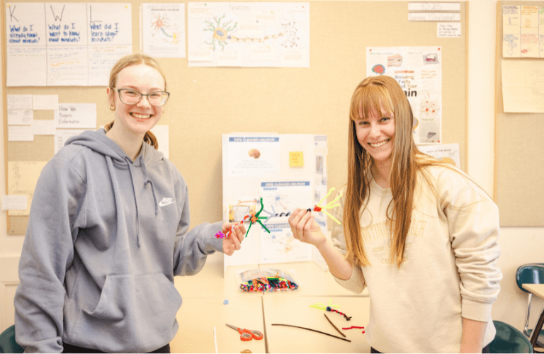 Two students hold models of neurons together