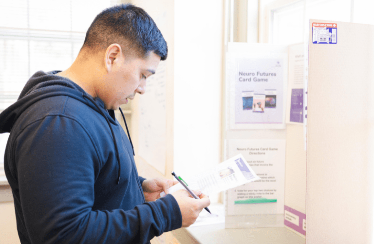 A students consults a resource in front of a presentation board