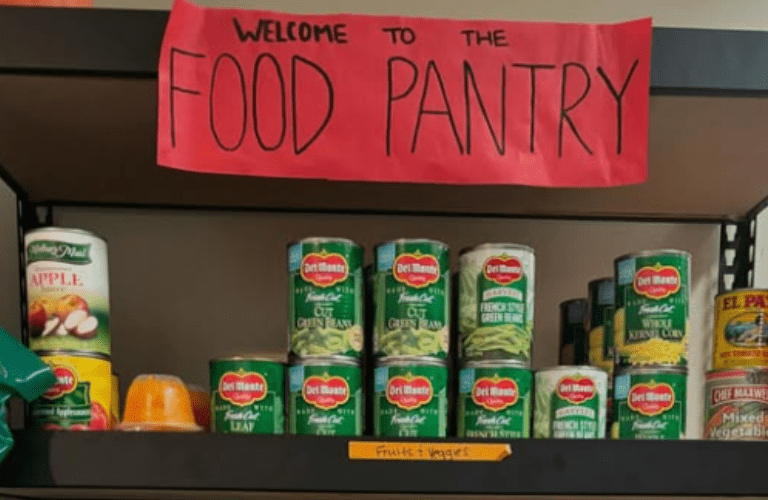 A sign saying &quot;Welcome to the Food Pantry&quot; above canned goods