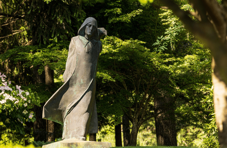 Statue of St. Benedict before green trees