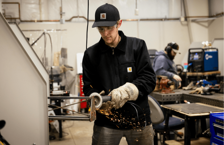 A student works with technical equipment, sparks flying