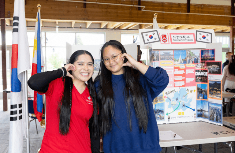 Students pose in front of a study abroad sandwich board
