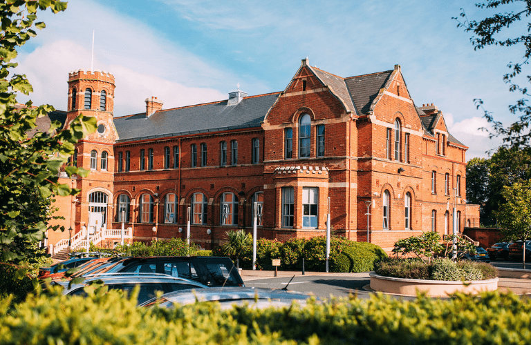 A sunkissed brick building surrounded by greenery
