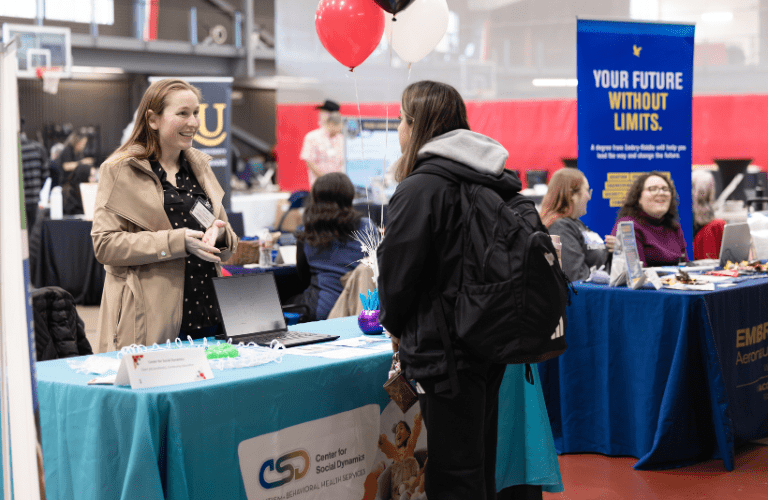 A student talks to a company representative tabling at a job fair