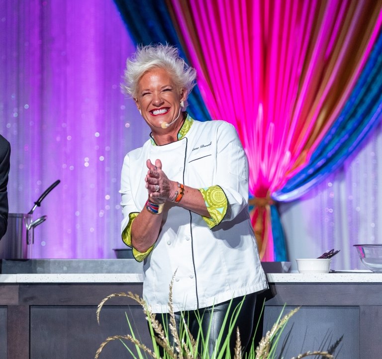 Chef Anne Burrell smiles and claps her hands on stage