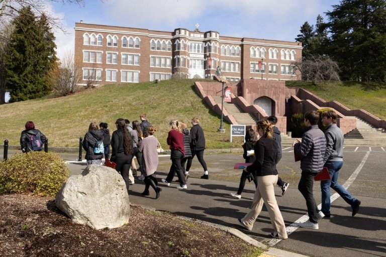 A tour group passes the bottom of the hill with Old Main in the background