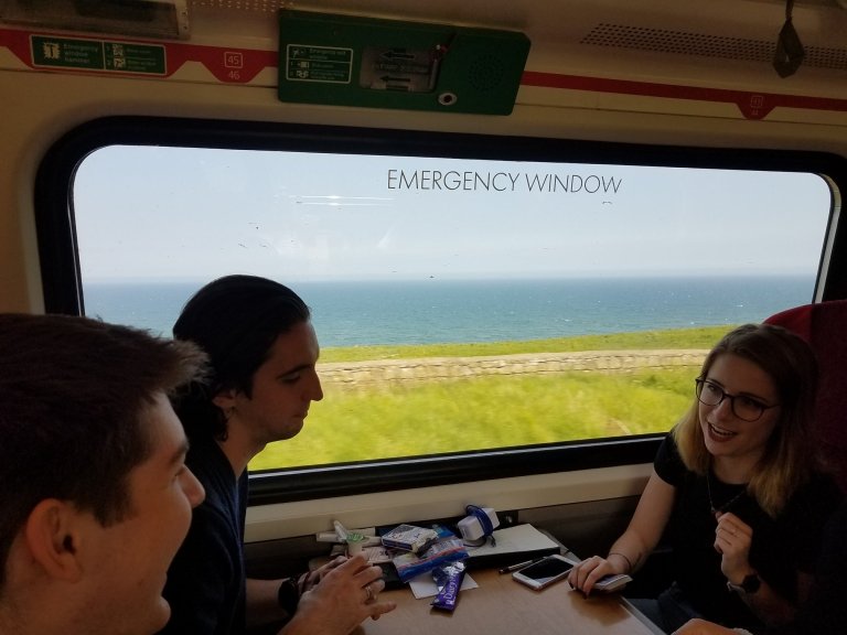 Students sitting around a table on a train in front of a window to the Scottish countryside