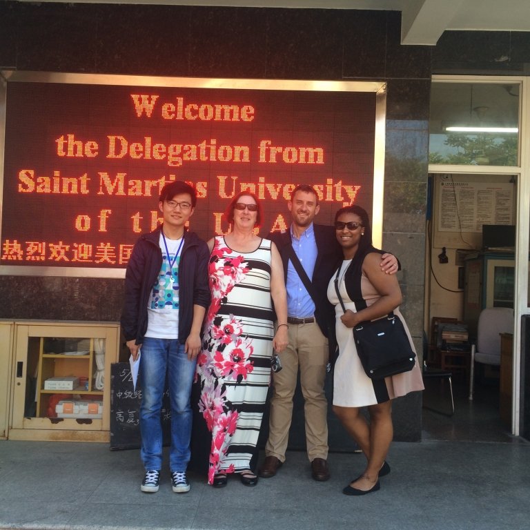 Students and professor in front of sign welcoming Saint Martin's University