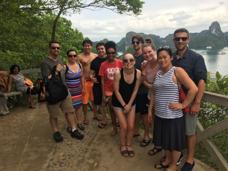 Students and professors gather at a vista overlooking a bay