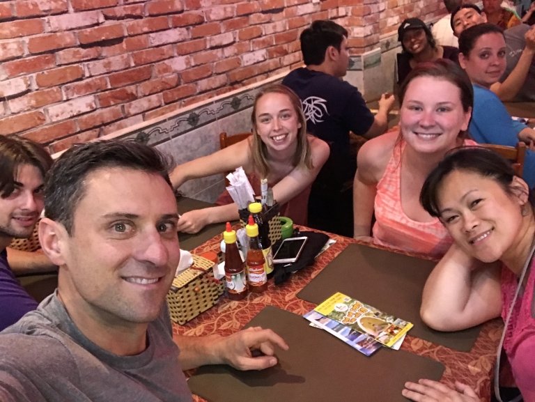 Professors and students sit around a restaurant table