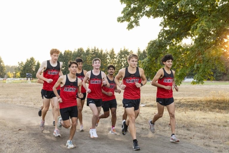 Cross country men's team runs in uniform in a field