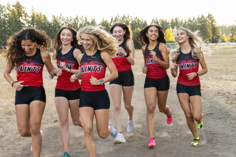 Women's cross country team running in uniform in field