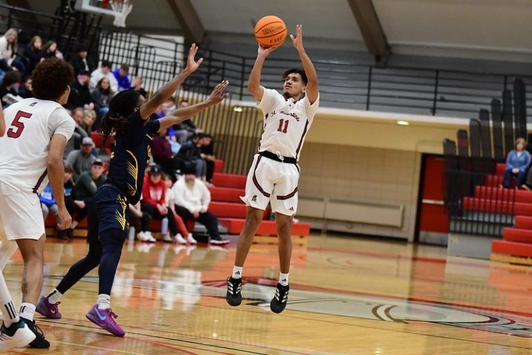 A student jumps to shoot the basketball while the other team tries to steal it