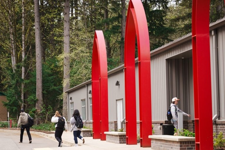 Students walk in front of building with big red arches