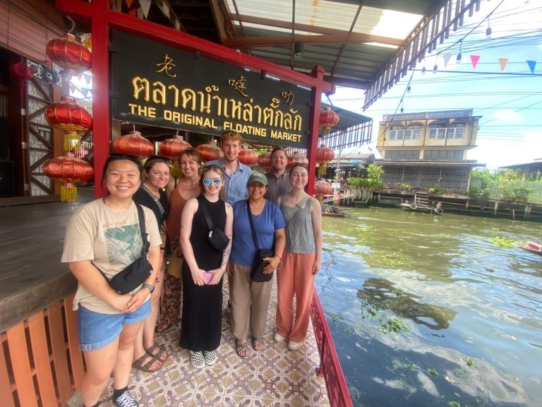 Students stand under sign in foreign language next to water