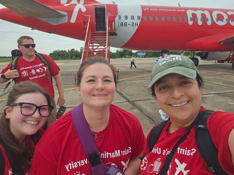 Saints in matching red t-shirts in front of red airplane