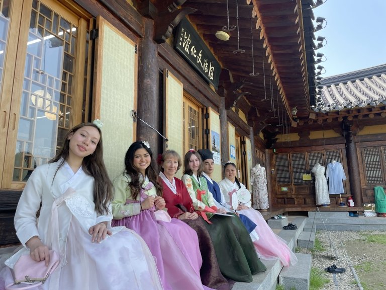 Students and faculty in traditional dress in front of Korean building