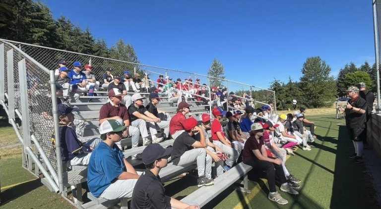 Students sit in risers outside listening to a coach