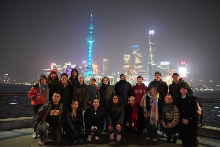 Students and faculty at night in front of lit up Shanghai cityscape