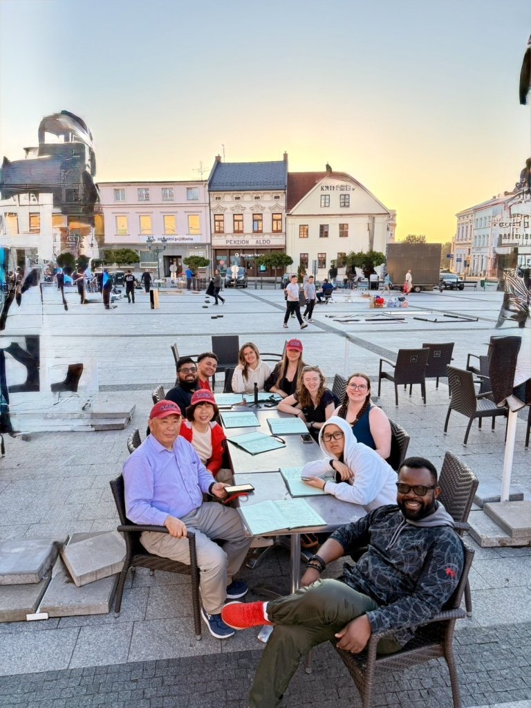 Students and faculty seated at table in plaza at dusk