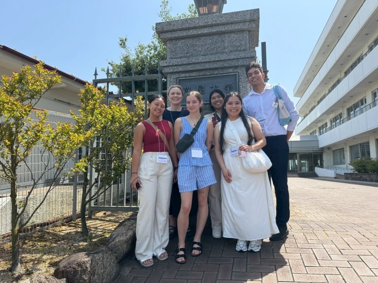 Students standing in front of gate on sunny day