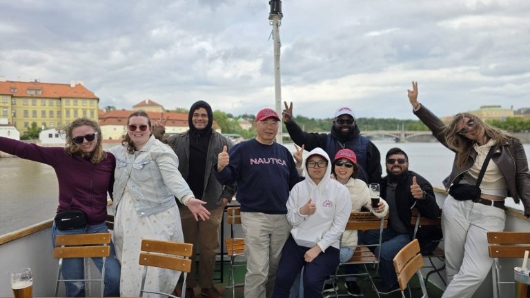 Students and faculty pose on back of a boat on the river
